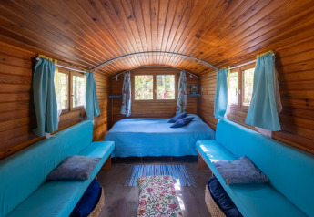 Interno della Gipsy wagon al Camping Des Randonneurs, Francia, con pareti in legno e divani azzurri.