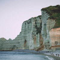Stunning white limestone cliffs on the coast near Yport, Normandy, France, with people walking below.