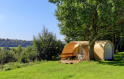 Tenda safari Coco Sweet al Camping La Colline in Belgio, circondata da alberi e prato verde lussureggiante.