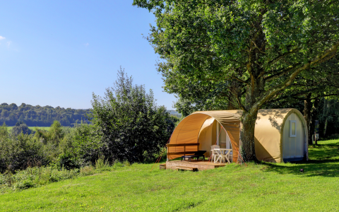 Tienda safari Coco Sweet en Camping La Colline, Bélgica, rodeada de árboles y paisaje verde y abierto.