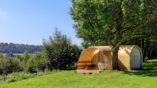 Tienda safari Coco Sweet en Camping La Colline, Bélgica, rodeada de árboles y paisaje verde y abierto.