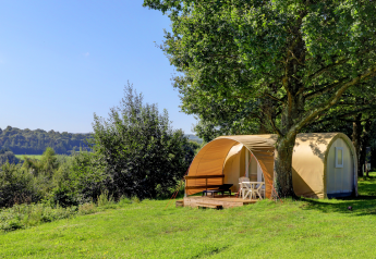 Tienda safari Coco Sweet en Camping La Colline, Bélgica, rodeada de árboles y paisaje verde y abierto.