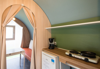 Interior de tienda safari Coco Sweet en Camping La Colline, Bélgica, con cocina americana y zona de estar.