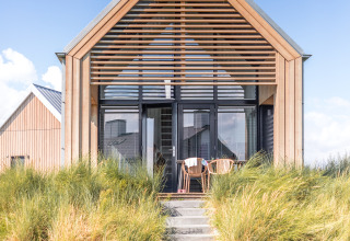 Cabaña moderna en Villa Oesterdam, Oesterdam Resort, Países Bajos, con fachada de madera y césped verde.