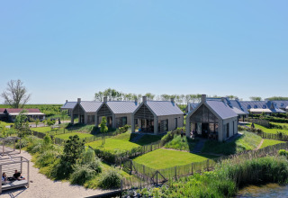 Modern lodges at Villa Oesterdam in Oesterdam Resort, Netherlands, surrounded by lush greenery and water.
