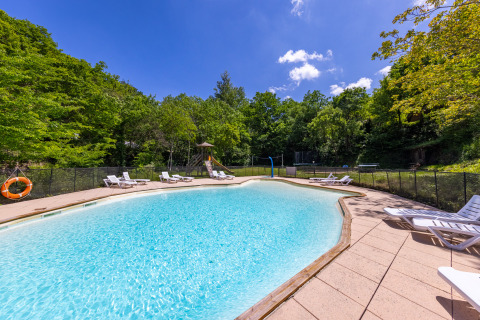Outdoor swimming pool with sun loungers and lush green trees at Camping Des Randonneurs holiday park in Occitanie.