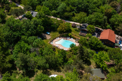 Vista aerea di Camping Des Randonneurs in Occitania, Francia, con piscina immersa tra alberi verdi.