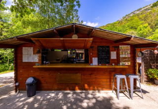 Wooden snack bar at Camping Des Randonneurs in Occitanie, France, set amidst lush greenery.