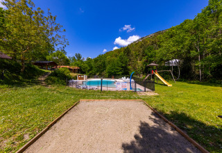 Outdoor view of Camping Des Randonneurs in Occitanie, France, with pool, playground, and pétanque court.