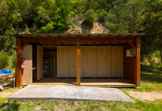 Houten buitentoiletten omgeven door natuur bij Camping Des Randonneurs in Occitanië, Frankrijk.