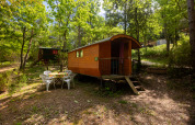 Foto di una Gipsy wagon senza bagno privato al Camping Des Randonneurs, immersa tra alberi verdi.