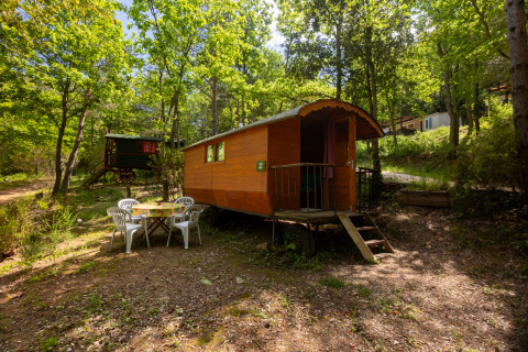Foto di una Gipsy wagon senza bagno privato al Camping Des Randonneurs, immersa tra alberi verdi.