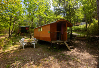 Photo of a Gipsy wagon without private bathroom at Camping Des Randonneurs, surrounded by forest trees.