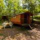 Foto de una caravana Gipsy sin baño privado en Camping Des Randonneurs, rodeada de árboles verdes.