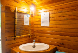 Håndvask og spejl i et træbeklædt badeværelse i en hytte på Camping Des Randonneurs, Frankrig.