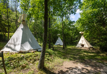 Tipi senza servizi igienici in una foresta verde al Camping Des Randonneurs, Francia, con luce solare.