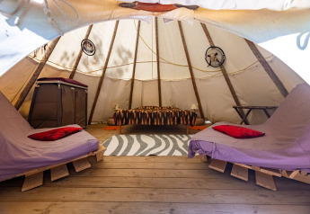 Vista interna di una tenda tipi con letti, pavimento in legno e acchiappasogni al Camping Des Randonneurs, Francia.