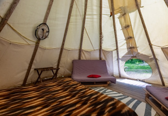 Vista interna di un tipì senza servizi igienici al Camping Des Randonneurs in Francia, con letti e coperta.