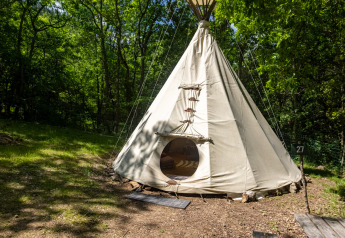 Tipi senza servizi igienici al Camping Des Randonneurs in Francia, circondato da alberi e una panchina.