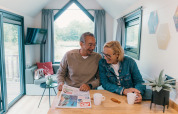 Couple senior partage un café et lit le journal dans une tiny house au Holiday Park Sallandshoeve, Pays-Bas.