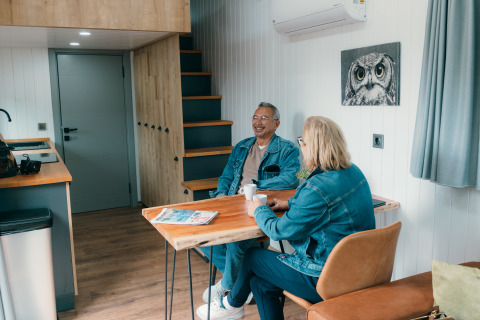Deux seniors prennent un café dans une Tiny House au Holiday Park Sallandshoeve, Pays-Bas.