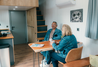 Deux seniors prennent un café dans une Tiny House au Holiday Park Sallandshoeve, Pays-Bas.