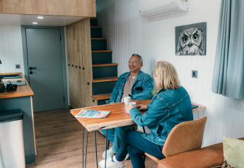 Deux seniors prennent un café dans une Tiny House au Holiday Park Sallandshoeve, Pays-Bas.