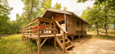 Tenda Safari Lodge al Camping Centro Vacanze San Marino, con veranda in legno immersa nella natura verde.