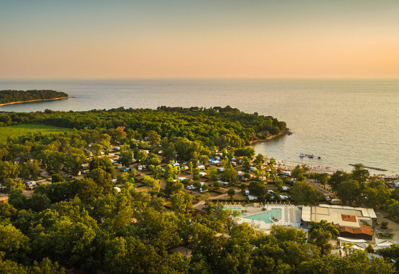 Vista aérea del Aminess Planet Camping Maravea Resort en Istria, Croacia, rodeado de árboles y la costa.