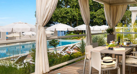 Espace repas extérieur avec vue sur la piscine, transats et parasols à Aminess Planet Camping Maravea Resort en Istrie.