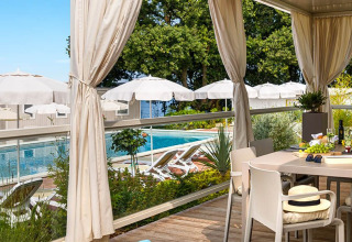 Espace repas extérieur avec vue sur la piscine, transats et parasols à Aminess Planet Camping Maravea Resort en Istrie.