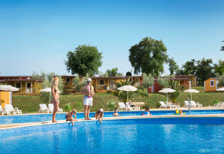 Gezinnen ontspannen bij het zwembad met ligstoelen en parasols op Aminess Planet Camping Maravea Resort in Istrië, Kroatië.