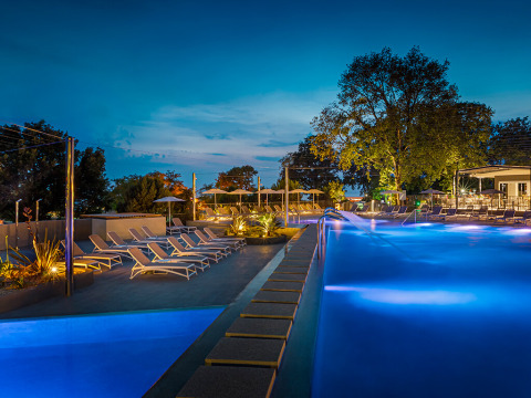 Piscina illuminata all'Aminess Planet Camping Maravea Resort, Istria, Croazia, con lettini al tramonto.