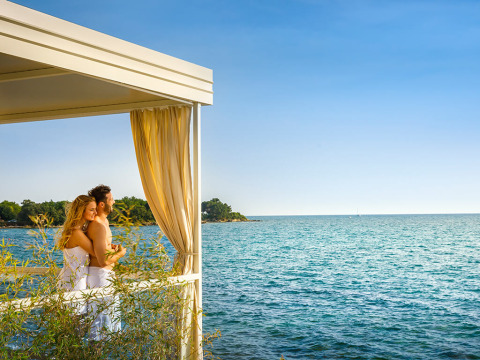 Coppia che si gode la vista mare da una terrazza con tende presso Aminess Planet Camping Maravea Resort, Istria, Croazia.