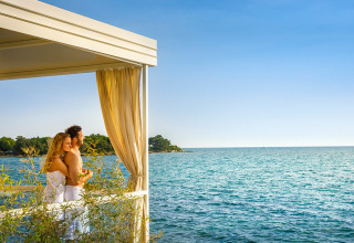 Couple profitant de la vue sur la mer depuis une terrasse avec rideaux à Aminess Planet Camping Maravea Resort, Istrie, Croatie.