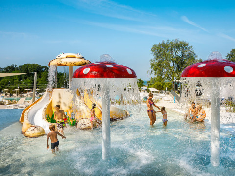 Children playing in a kids’ waterpark with slides and mushroom fountains at Aminess Planet Camping Maravea Resort.