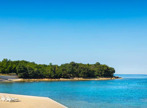 Uitzicht op het helderblauwe water en groene kust bij Aminess Planet Camping Maravea Resort in Istrië, Kroatië.