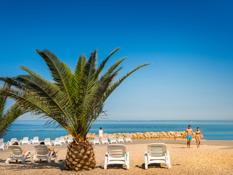 Palma, lettini e bagnanti lungo la spiaggia di ciottoli all’Aminess Planet Camping Maravea Resort in Istria.