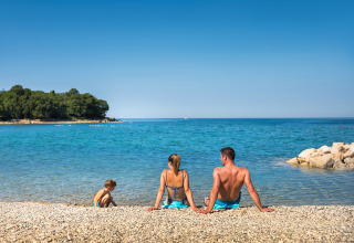 Famille se détendant sur une plage de galets à Aminess Planet Camping Maravea Resort, Istrie, Croatie.