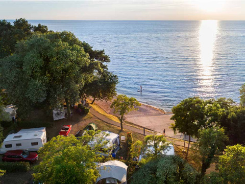 Kampeerplekken met caravans en tenten aan zee in Aminess Planet Camping Maravea Resort bij zonsondergang.