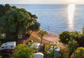 Kampeerplekken met caravans en tenten aan zee in Aminess Planet Camping Maravea Resort bij zonsondergang.