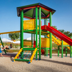 Kinderen spelen op een kleurrijke speeltuin met glijbaan en schommels bij Aminess Planet Camping Maravea Resort in Istrië.