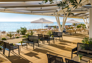 Open-air seaside dining area with sunlit seating and umbrellas at Aminess Planet Camping Maravea Resort, Istria, Croatia.