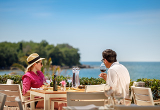 Una coppia gusta vino e cibo sul mare all’Aminess Maravea Camping Resort in Istria, Croazia.