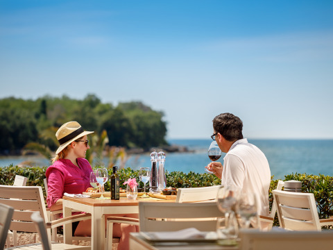 A couple enjoys wine and a seaside meal at Aminess Maravea Camping Resort in Istria, Croatia.