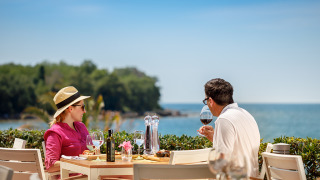 Een stel geniet van wijn en een maaltijd aan zee bij Aminess Maravea Camping Resort in Istrië, Kroatië.