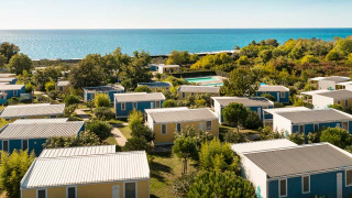 Bungalow colorati immersi nel verde si affacciano sul mare in una giornata soleggiata e limpida.