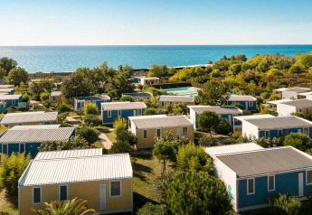 Bungalow colorati immersi nel verde si affacciano sul mare in una giornata soleggiata e limpida.