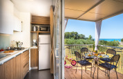 Cucina moderna in una cabina che si apre su una terrazza coperta con vista mare e tavolo per la colazione.