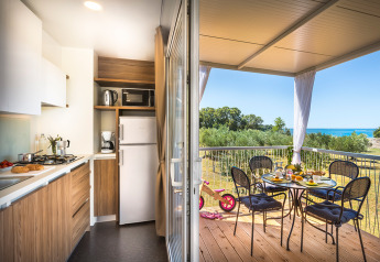 Cucina moderna in una cabina che si apre su una terrazza coperta con vista mare e tavolo per la colazione.